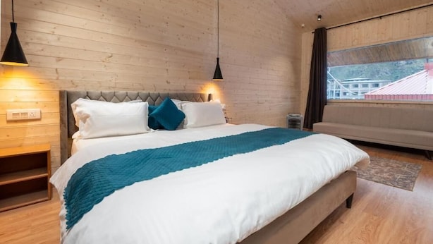 A bedroom with a bed, wooden walls, a window, and a nightstand.