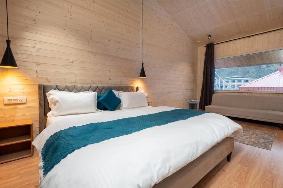 Een slaapkamer met een bed, houten wanden, een raam en een nachtkastje.
