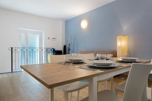 Ein Essbereich mit Holztisch, weißen Stühlen und blauer Wand.