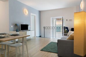 Een moderne woonkamer met een eethoek, een grijze bank, een houten tafel en een groen vloerkleed.