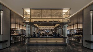 A modern hotel lobby with a central seating area, a high ceiling with a decorative panel, and a bar area on either side. - Steigenberger Icons Guizhou Xiaoqikong (Qiannan)