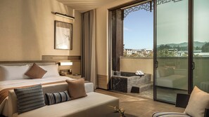 A hotel room with a bed, a nightstand, a desk, a chair, a balcony with a view of buildings and hills. - Steigenberger Icons Guizhou Xiaoqikong (Qiannan)