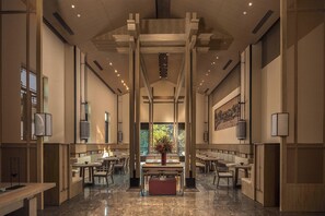 A spacious, modern interior with high ceilings, wooden beams, and a central floral arrangement.