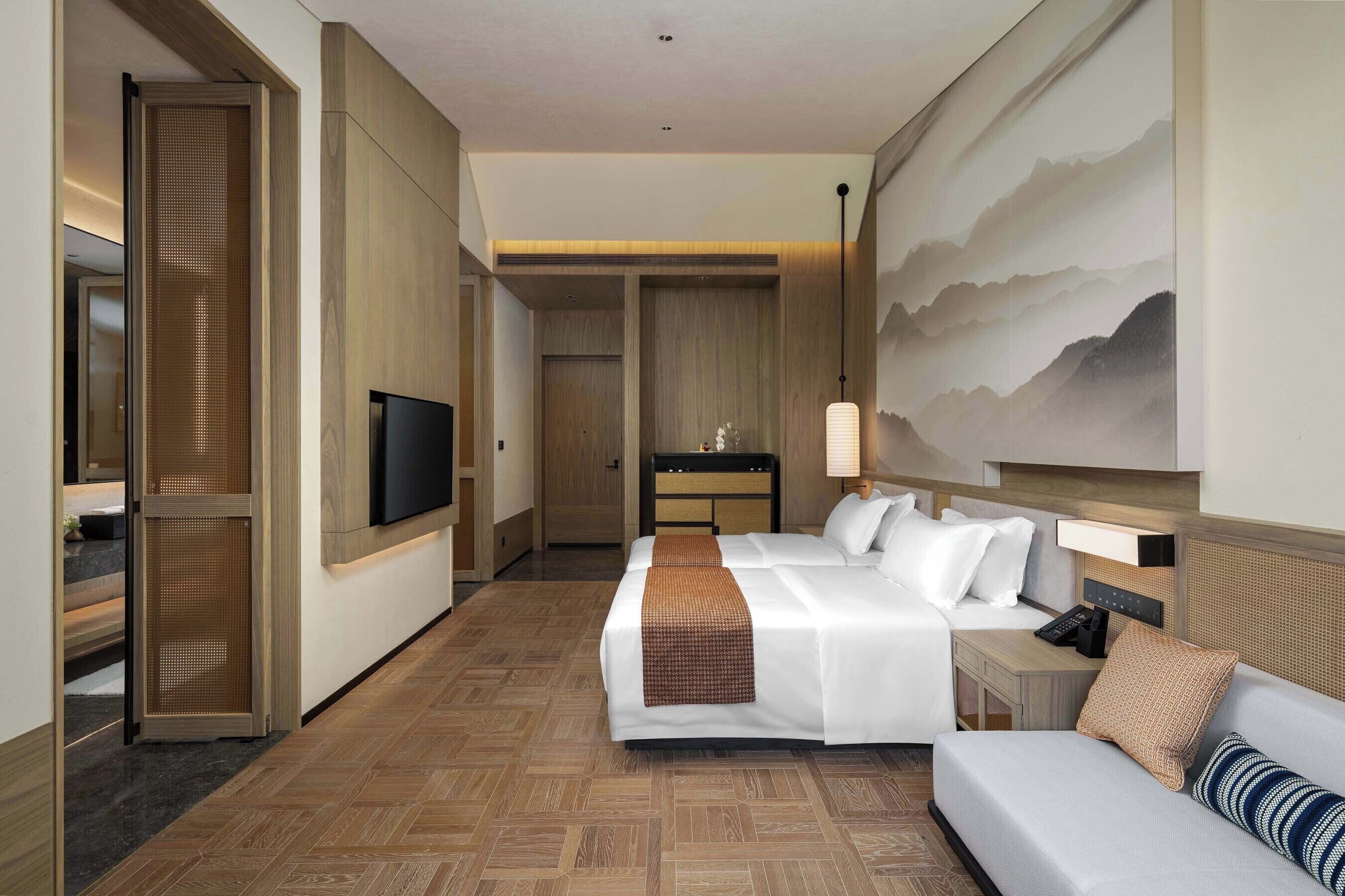 Habitación de hotel con cama, sofá, televisión, escritorio y un cuadro en la pared.