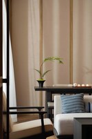 A modern living room with a sofa, a small table, a potted plant, and a chair.