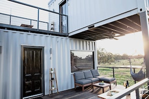A modern outdoor deck with a sofa, a table, and a hammock.