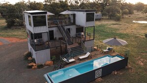 A modern, multi-level outdoor living space with a pool, deck, and outdoor seating area.