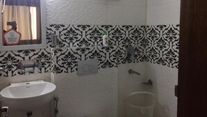 A bathroom with a sink, mirror, shower, and patterned tiles. - The Prince Inn (Gurugram)