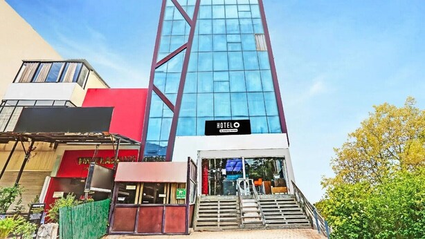 A modern hotel building with a prominent glass facade, a sign indicating it's a hotel, and a staircase leading to the entrance. - The Prince Inn (Gurugram)
