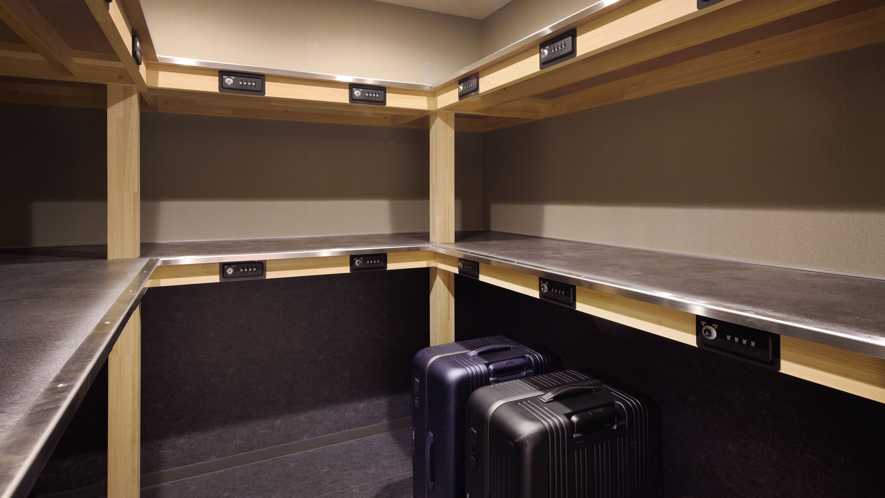 A hotel room with a kitchenette, a single bed, and a suitcase on the floor.