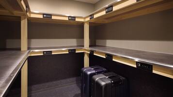 A hotel room with a kitchenette, a single bed, and a suitcase on the floor.
