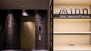 Un ascensore con un display digitale, un muro in mattoni e un cartello che recita 'Minn your second home'.
