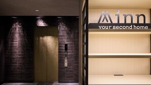 An elevator with a digital display, a brick wall, and a sign reading 'Minn your second home'. - Minn Namba Nipponbashi (Osaka)