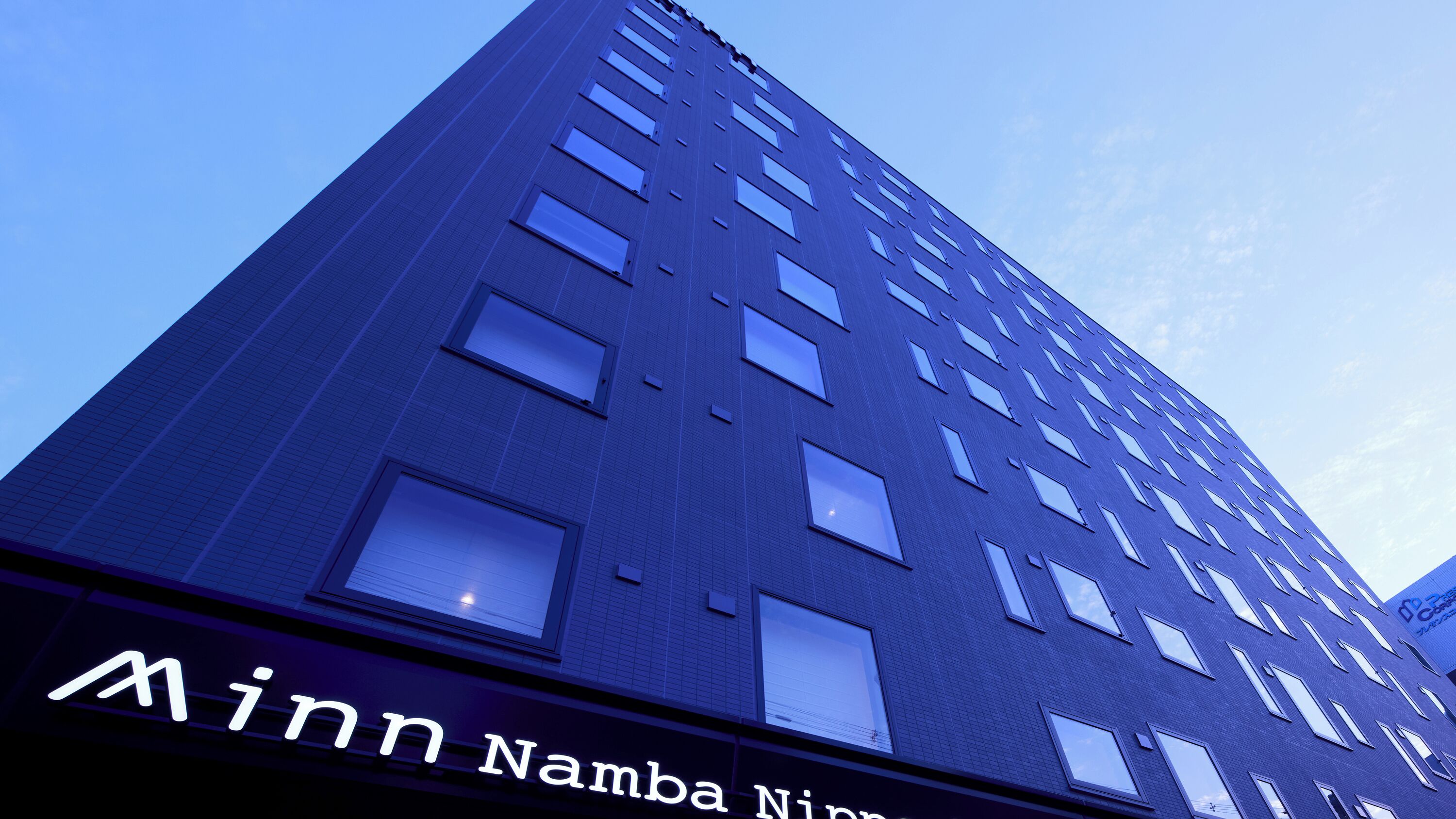 A tall building with a sign reading 'Minna Namba Nippu'.