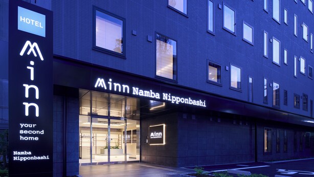 Ingresso di un hotel con un cartello che riporta 'Minna Nipponbashi' e 'Min Inn'.