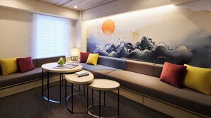 A modern living room with a sofa, two round tables, a lamp, and a wall mural.