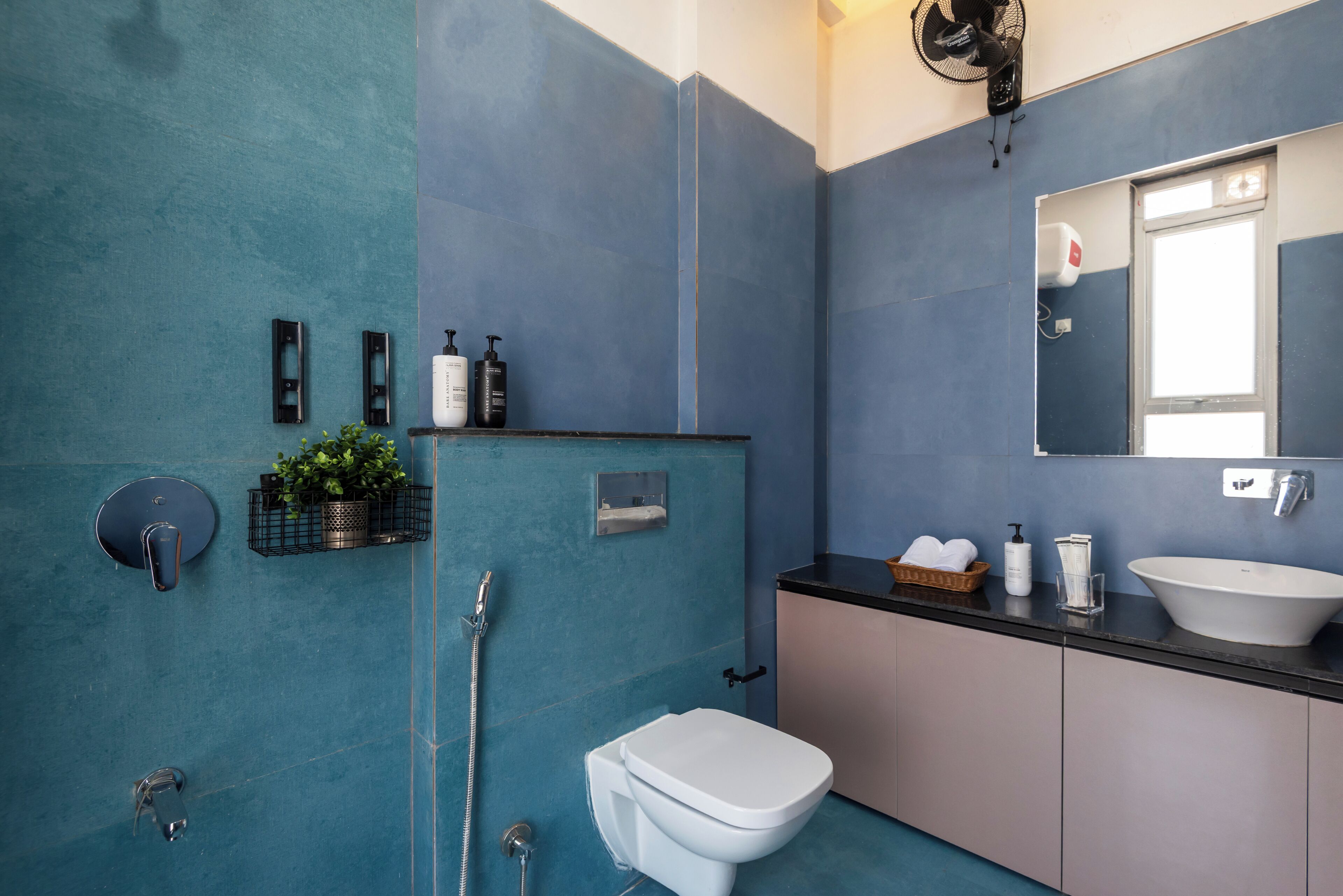 Une salle de bain avec des toilettes blanches, un lavabo, un miroir et une douche.