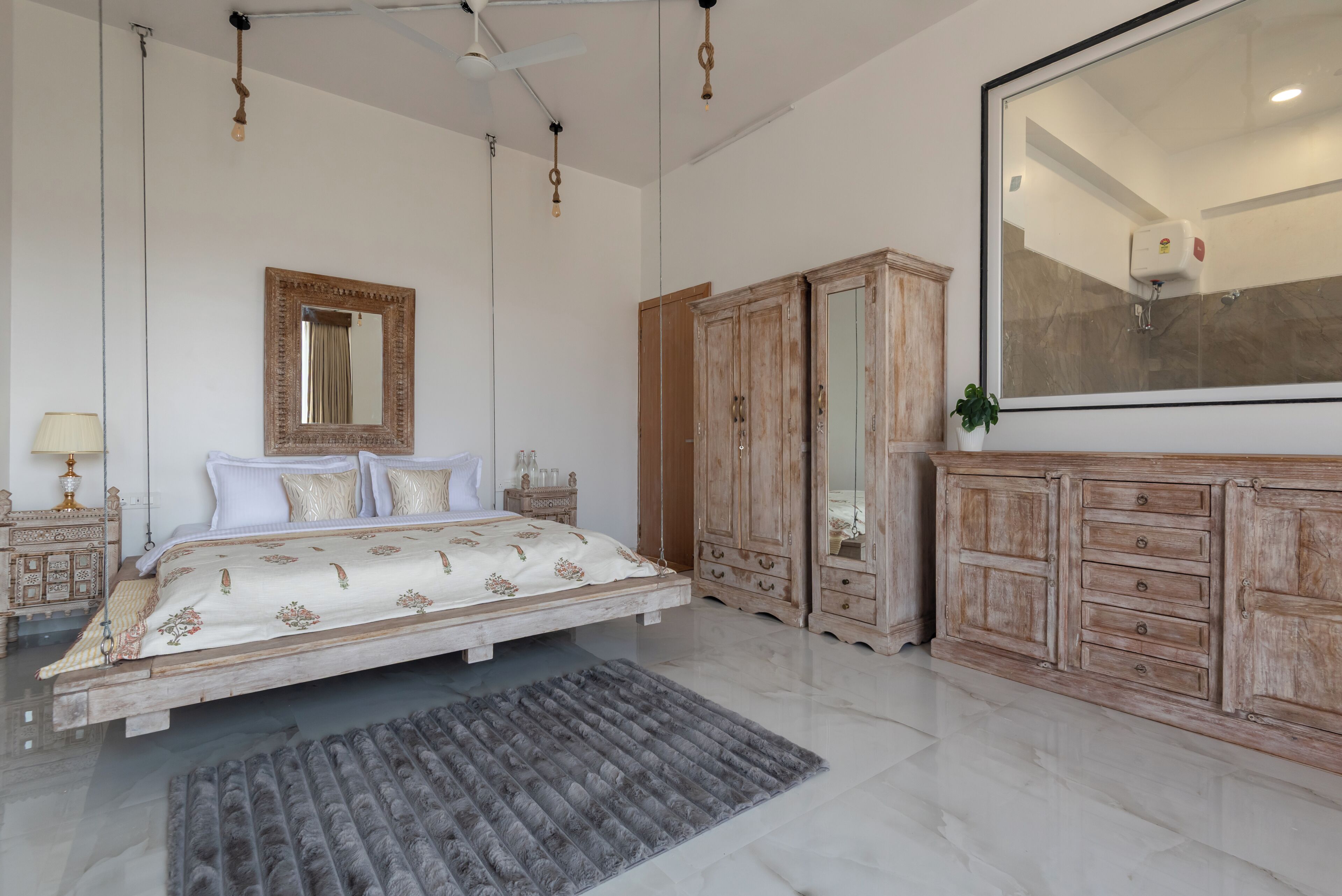 A bedroom with a bed, a large mirror, wooden wardrobe, and a ceiling fan.