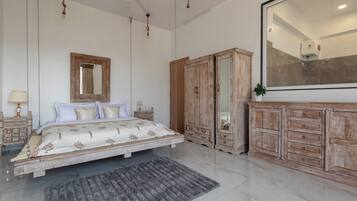 A bedroom with a bed, a large mirror, wooden wardrobe, and a ceiling fan.