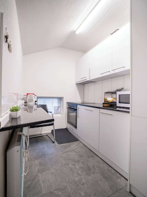 A modern kitchen with white cabinets, a built-in oven, and a microwave.