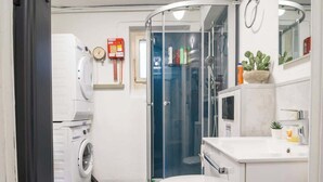 A compact bathroom with a toilet, sink, shower, and washing machine.