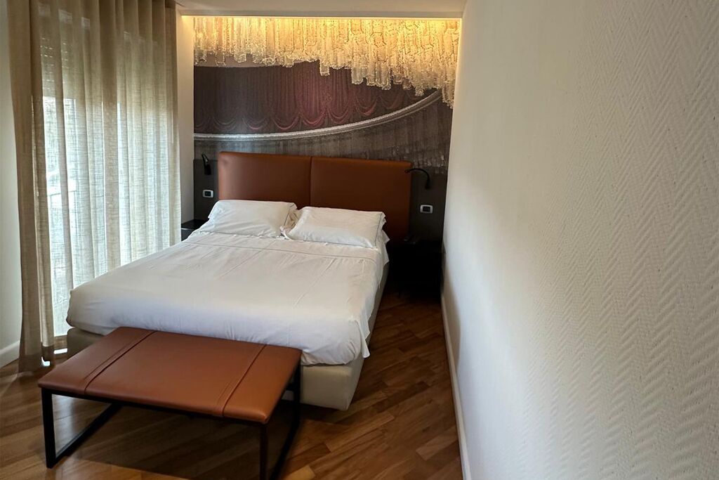 Une chambre d’hôtel comprenant un lit, une banquette, une table de chevet et un mur décoratif.