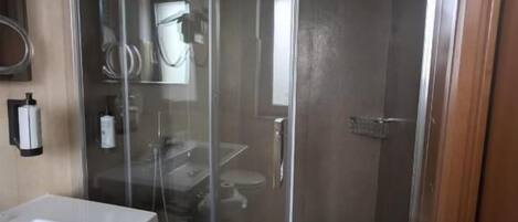 A modern bathroom with a glass-enclosed shower, a white sink, and a mirror.