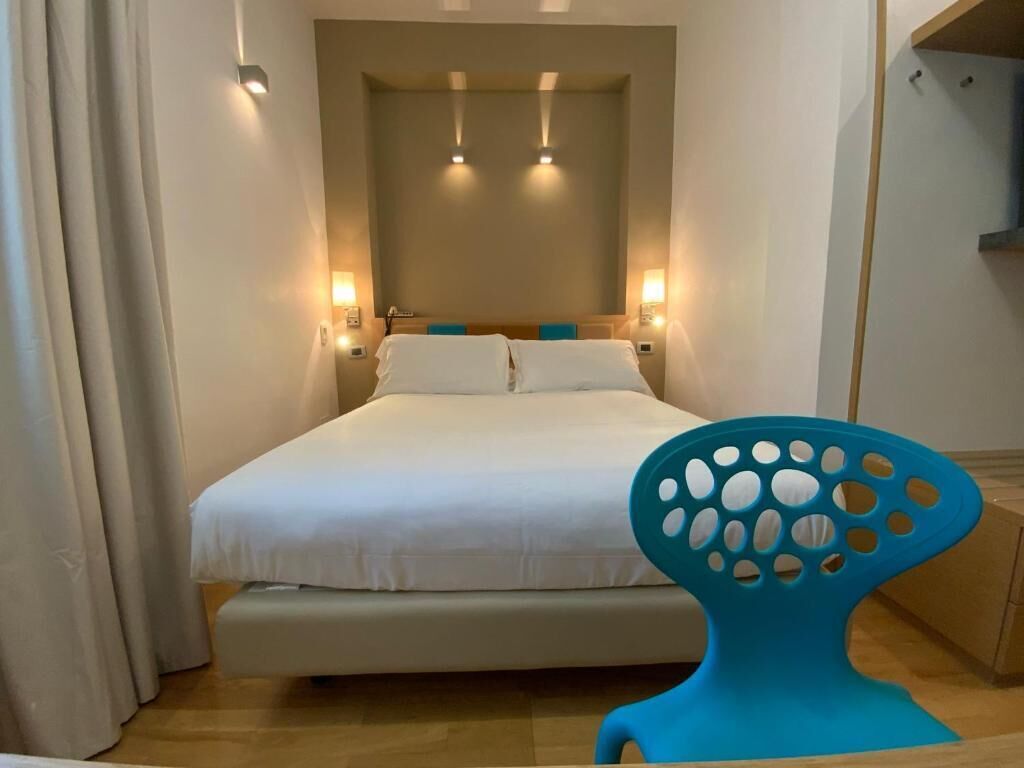 Quarto com cama, abajures, uma cadeira e espelho.