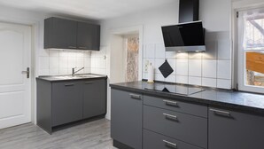 A modern kitchen with dark cabinets, a countertop, a sink, and a window with a view. - Apartment 'Stadthaus' with Private Terrace, Balcony and Wi-Fi (Mellrichstadt)