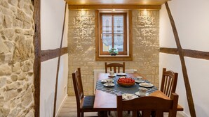 A dining area with a stone wall, wooden beams, a table set with plates, cups, and a fruit tart. - Apartment 'Stadthaus' with Private Terrace, Balcony and Wi-Fi (Mellrichstadt)