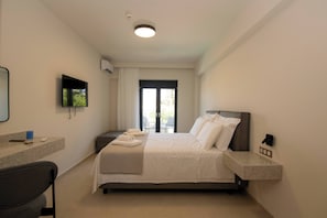 Ein Hotelzimmer mit Bett, Schreibtisch, Stuhl, Fernseher und Fenster.