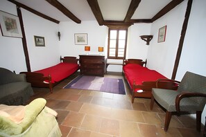 Una habitación con dos camas individuales, un aparador de madera, una silla y un sofá.