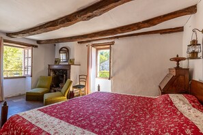 Een kamer met een bed, een stoel, een open haard en een raam.