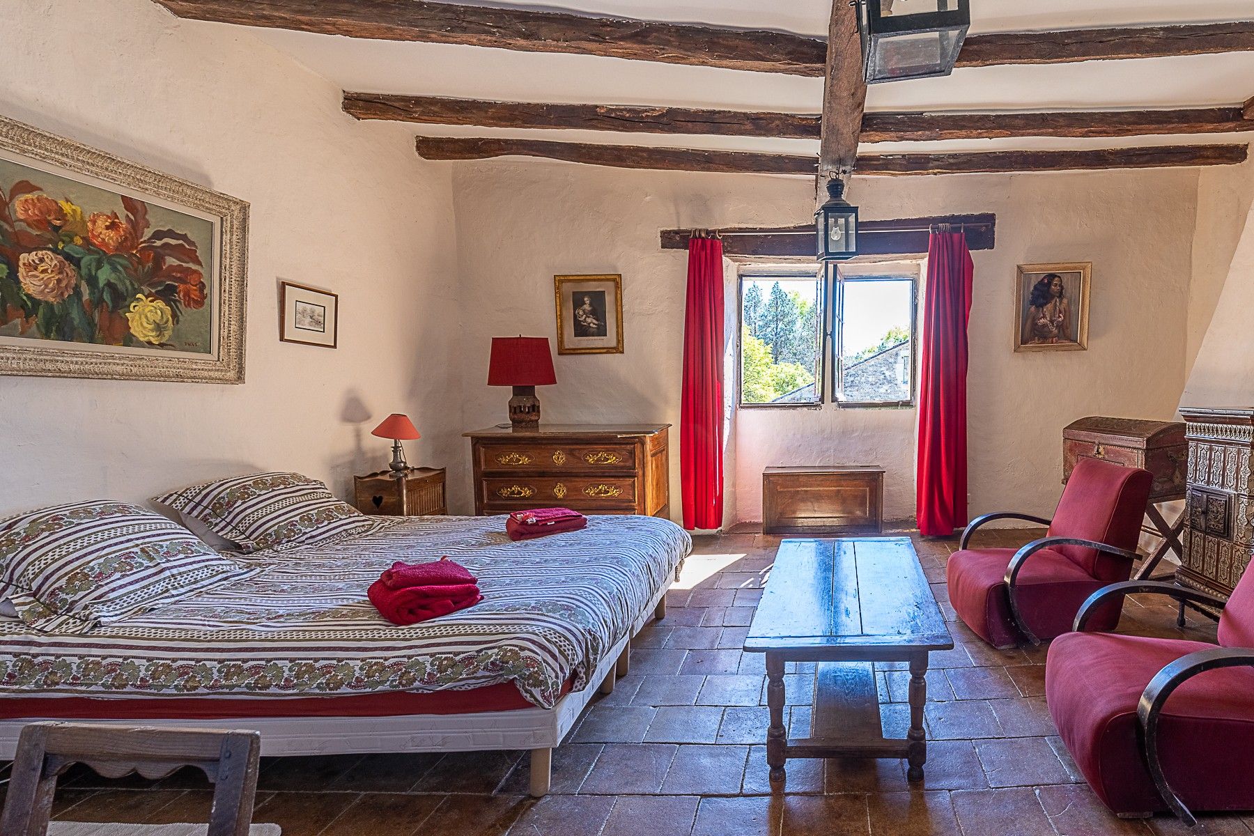 Een klassieke kamer met een bed, een houten tafel, een stoel en een raam met gordijnen.