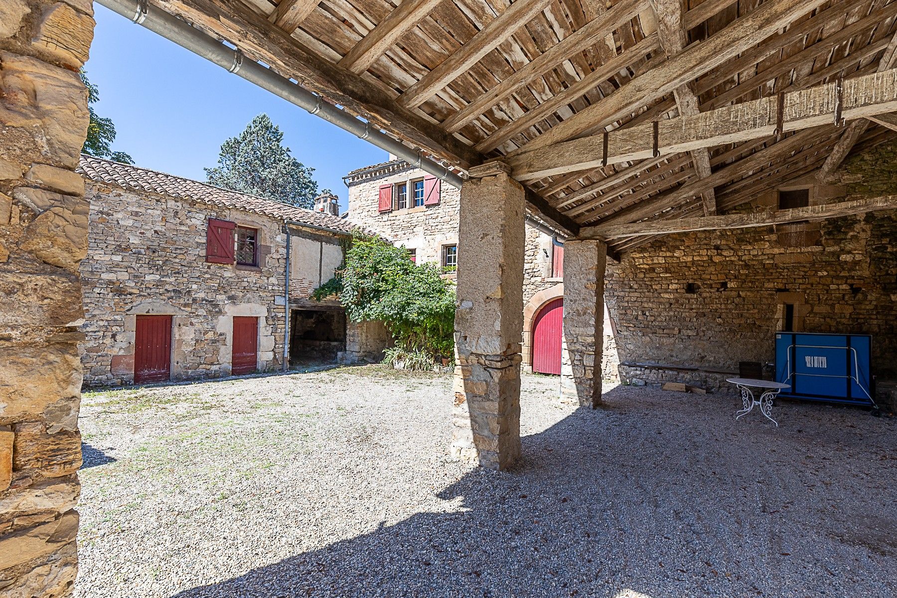 A courtyard with stone buildings, a wooden ceiling, and a blue cabinet.