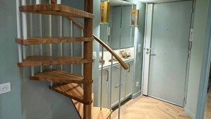 A spiral staircase with wooden steps and metal railings, leading to a room with a herringbone floor and a door with a mirror. - Mediterranean Dream - Carré d'Or (Nice)