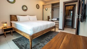 A bedroom with a wooden bed, bedside tables, a TV, and a walk-in closet. - Modern 2 Bedroom Westlands Nairobi,  with AC, Rooftop Pool, Gym, Squash Court (Nairobi)