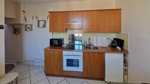 A compact kitchen with wooden cabinets, a built-in microwave, a stove, and a small refrigerator. - Le Centrale - Place Massena (Nice)