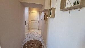 A narrow hallway with a patterned rug, a door at the end, and a shelf with a jar on the wall. - Le Centrale - Place Massena (Nice)