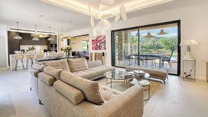 Una sala moderna con un sofá modular, una mesa de centro de vidrio y una zona de comedor con barra.