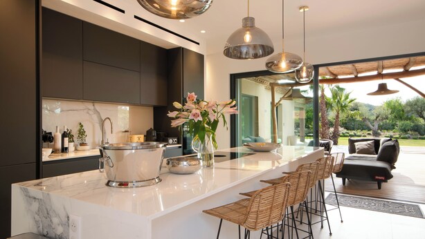 Una cocina moderna con encimera de mármol, electrodomésticos de acero inoxidable y una isla grande con taburetes de bar.