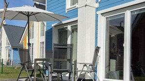 Ett bostadshus med en uteplats, utemöbler och ett stort parasoll.