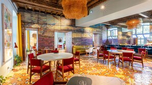 A restaurant with round tables, red chairs, and a colorful geometric floor pattern. - L'Arlatan (Arles)