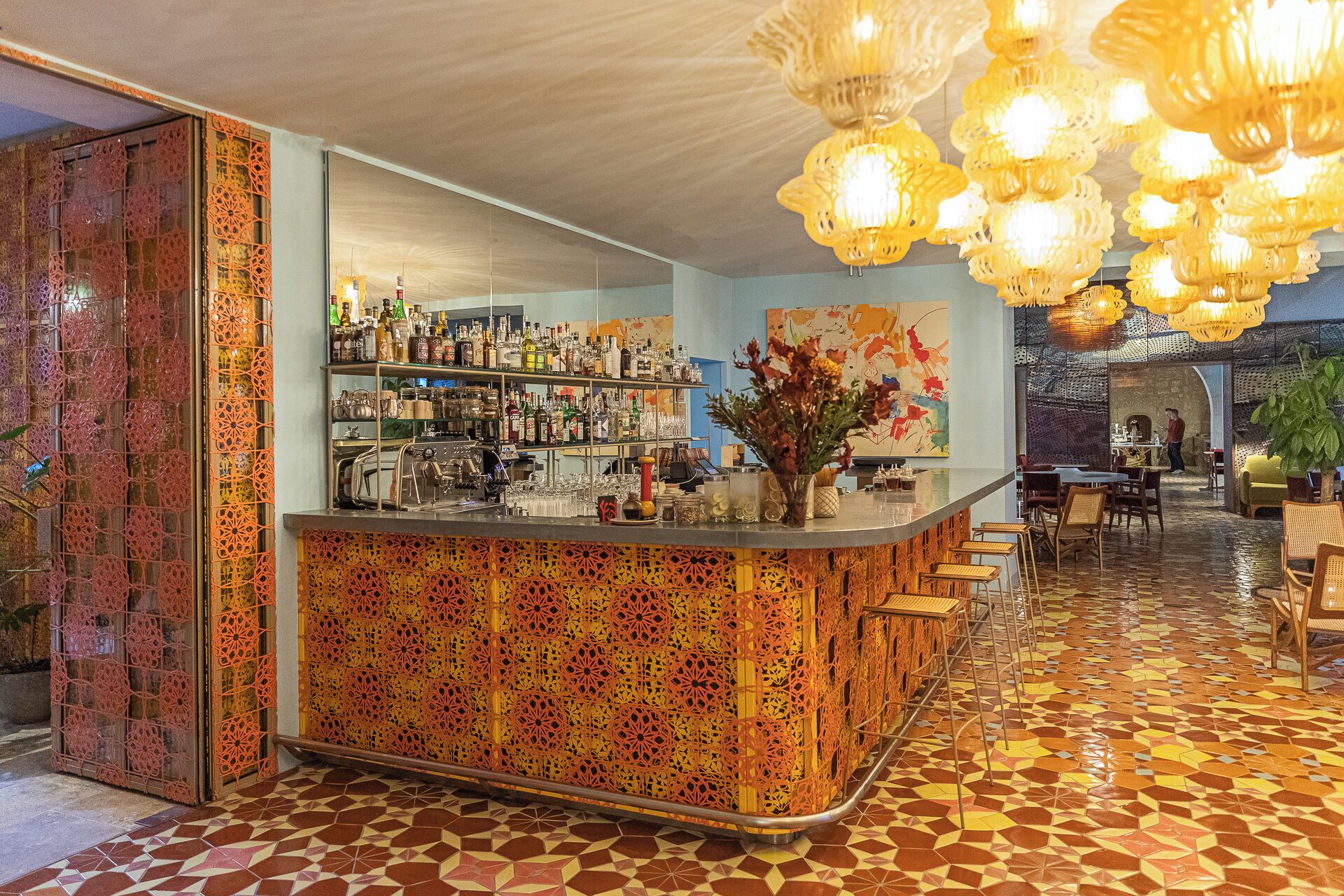 Eine Bar mit einer gemusterten Theke, Flaschenregalen und einer hängenden Leuchte.