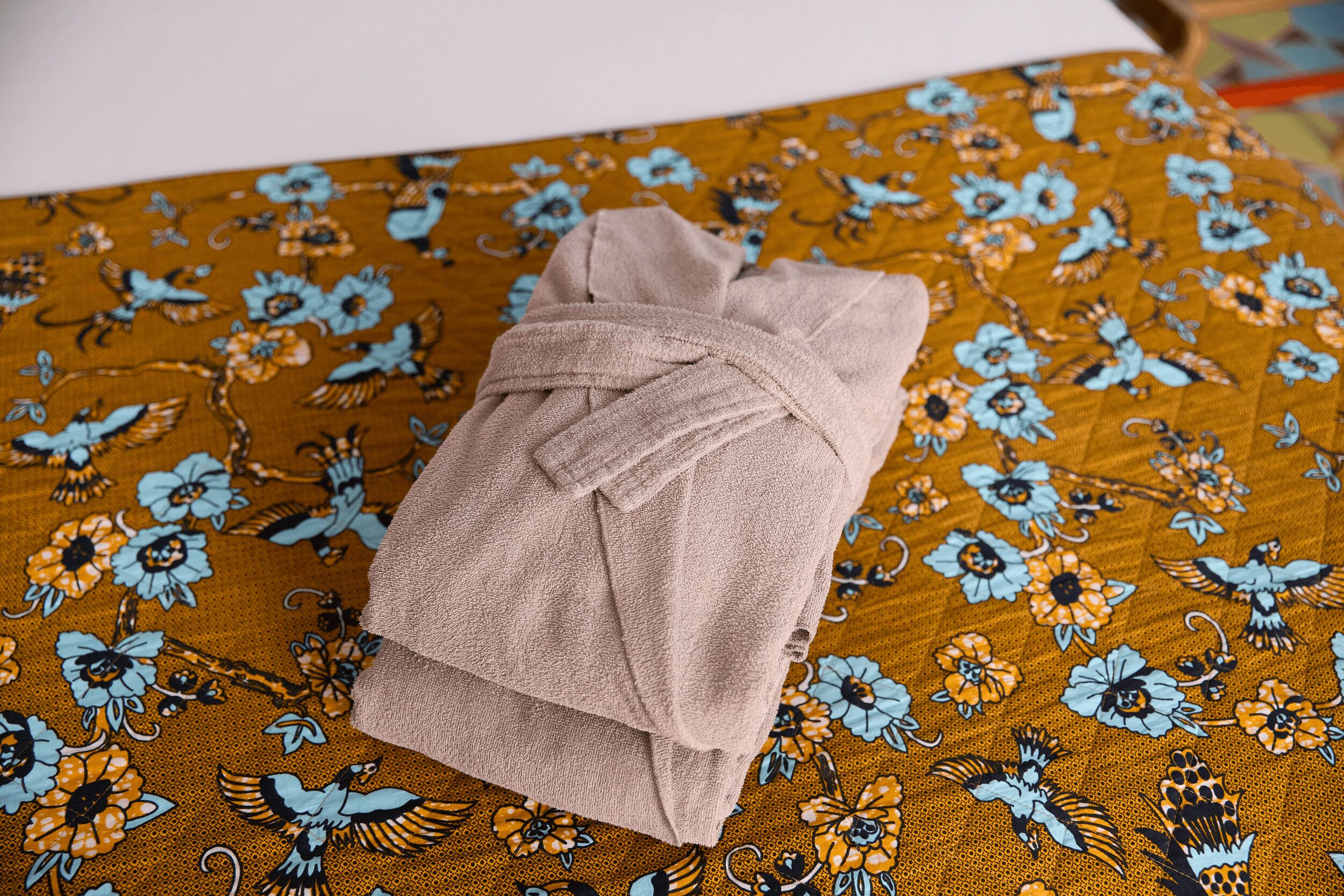 Una toalla sobre una cama con una colcha de estampado floral.