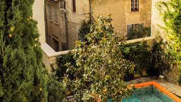 A courtyard with a swimming pool, surrounded by stone buildings with tiled roofs.