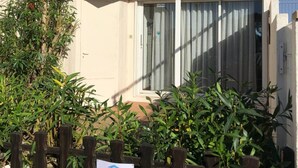 A building with a red facade, a window with white curtains, and a signboard in front. - Apartment 'Marina Oportoducap' with Lake View, Private Terrace and Air Conditioning (Agde)