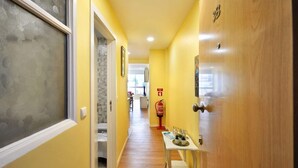 Um corredor com porta de madeira, um extintor e uma pequena mesa com objetos.