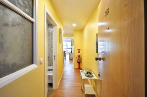 A hallway with a wooden door, a fire extinguisher, and a small table with items on it. - RH Charming Apartment Liberdade II (Braga)