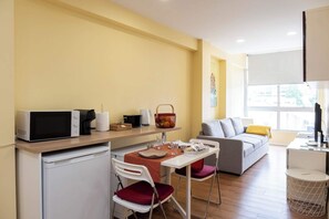 A compact living space with a kitchenette, a dining area, and a sofa. - RH Charming Apartment Liberdade II (Braga)